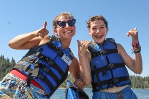 A counselor and a camper at a summer camp in California on Shaver Lake both smile with thumbs up