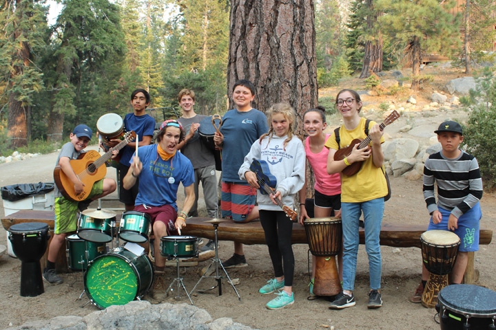 Campers and a counselor play guitars and drums at a summer camp in California